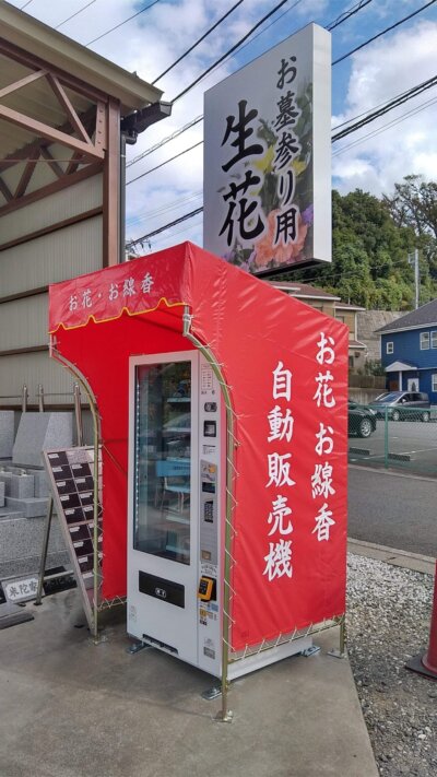 横浜日野公園墓地米陀石材店お花・お線香の自販機の斜め前画像です。